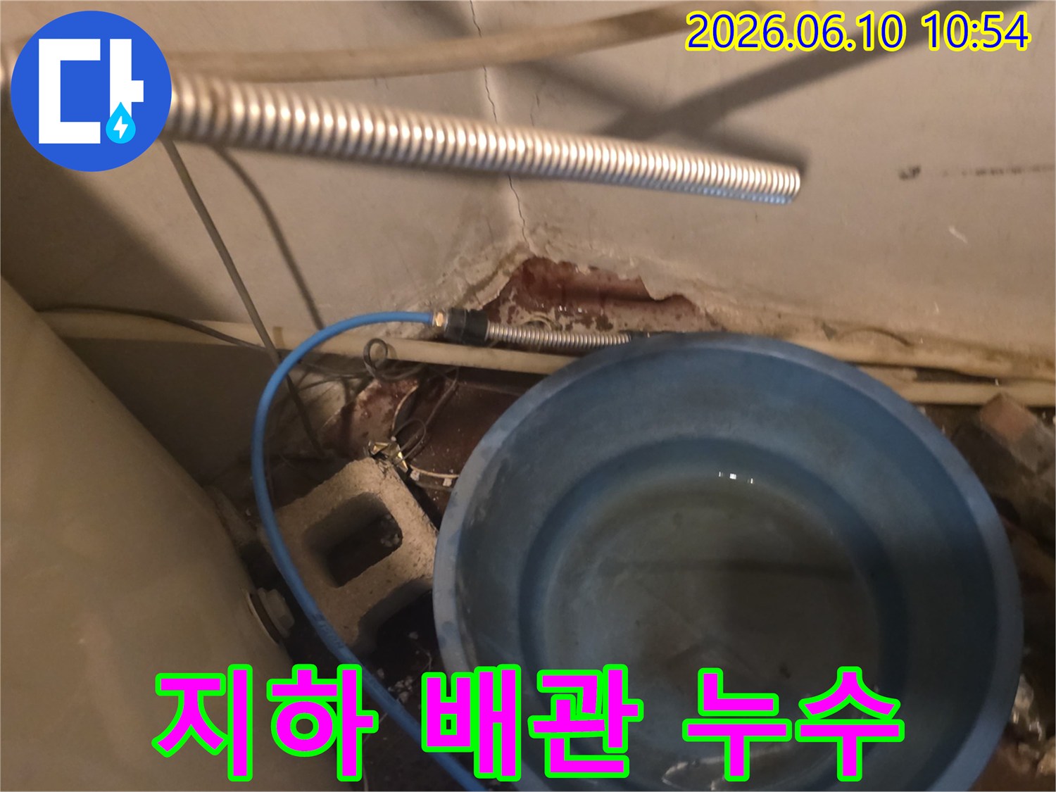 지하 공간에서 배관 누수로 인해-파란 양동이에 물이 고인-현장 상황을 보여주는 사진