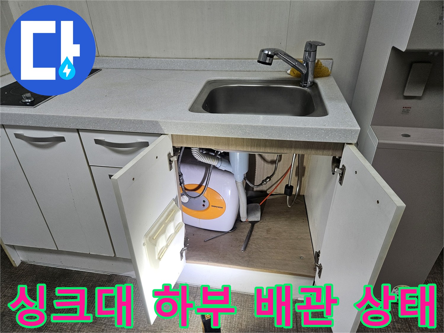 주방 싱크대 하부장 내부의 배관과 세탁기 연결 호스 모습