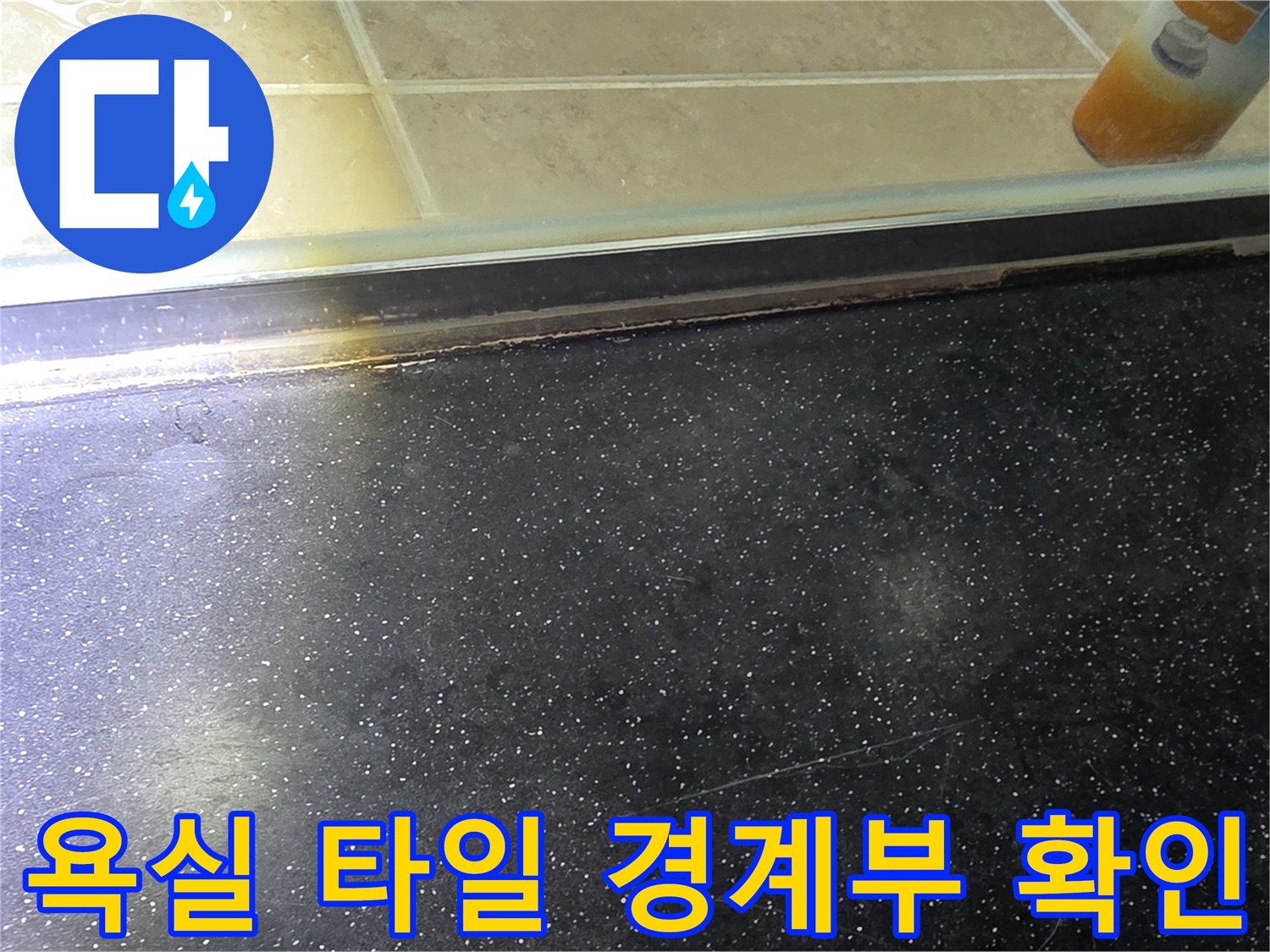어두운 색상의 욕실 바닥 타일과 밝은 벽면 타일의 접합부 상세 사진