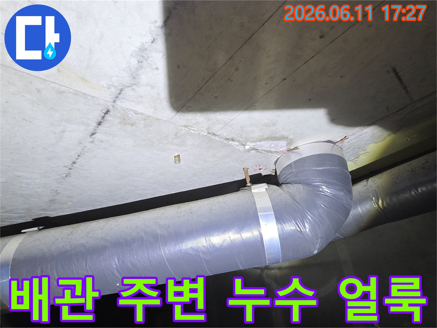 회색 배관과 연결된 천장 부위에서 나타난 물 얼룩과 손상 흔적을 상세히 보여주는 이미지