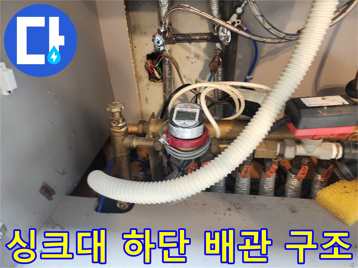 금속 밸브와 주름 호스가 연결된 싱크대 밑 배관 모습