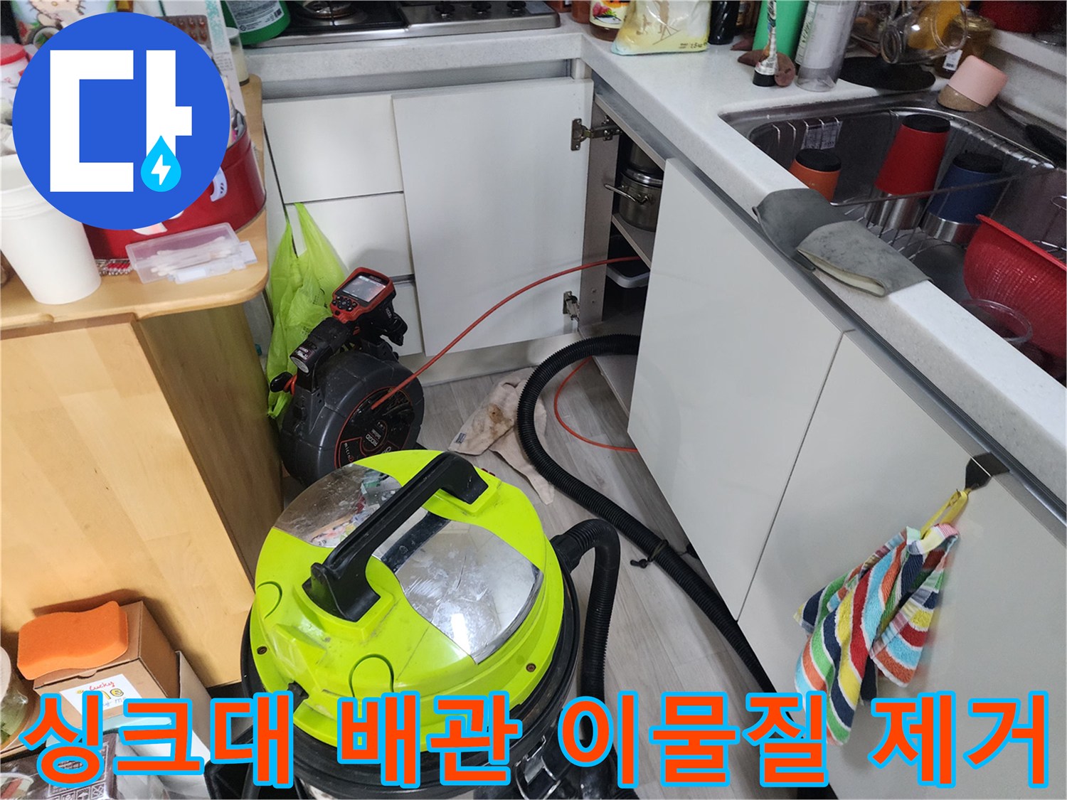 싱크대 아래쪽 배관에 쌓인 오물을 석션기로 빨아들이는 작업 장면입니다.