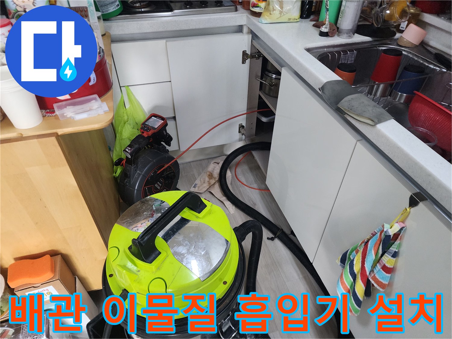 싱크대 아래쪽 배관에서 올라온 찌꺼기를 제거하기 위해 배치된 석션 장비와 호스입니다.