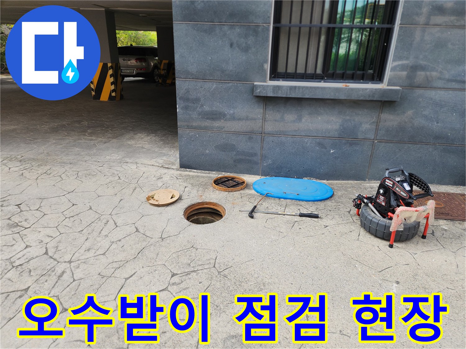 건물 외부 주차장 바닥-열려있는 오수받이와 고압세척 장비