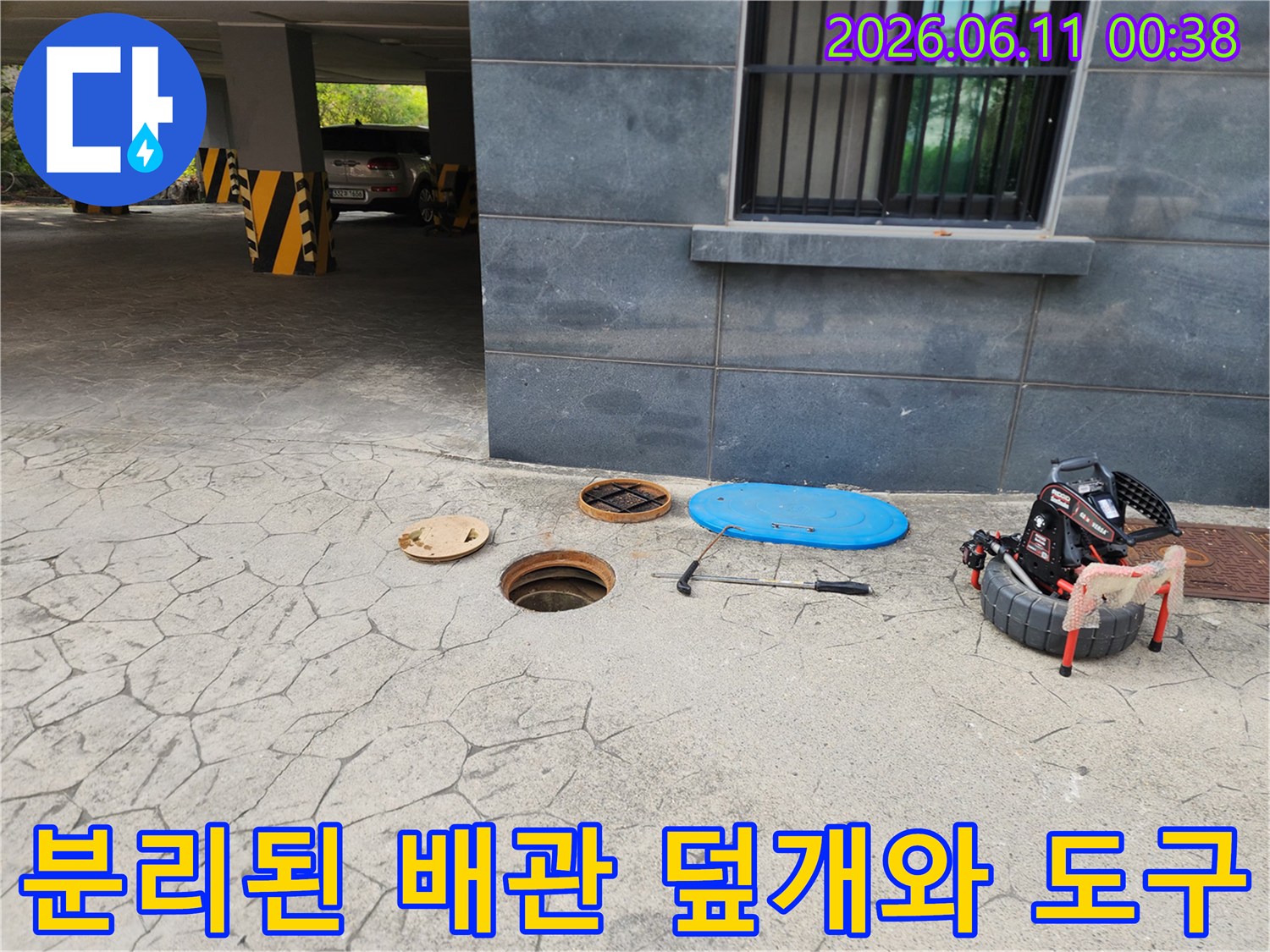 주차장 바닥의 분리된 맨홀 뚜껑과 작업 장비 세트