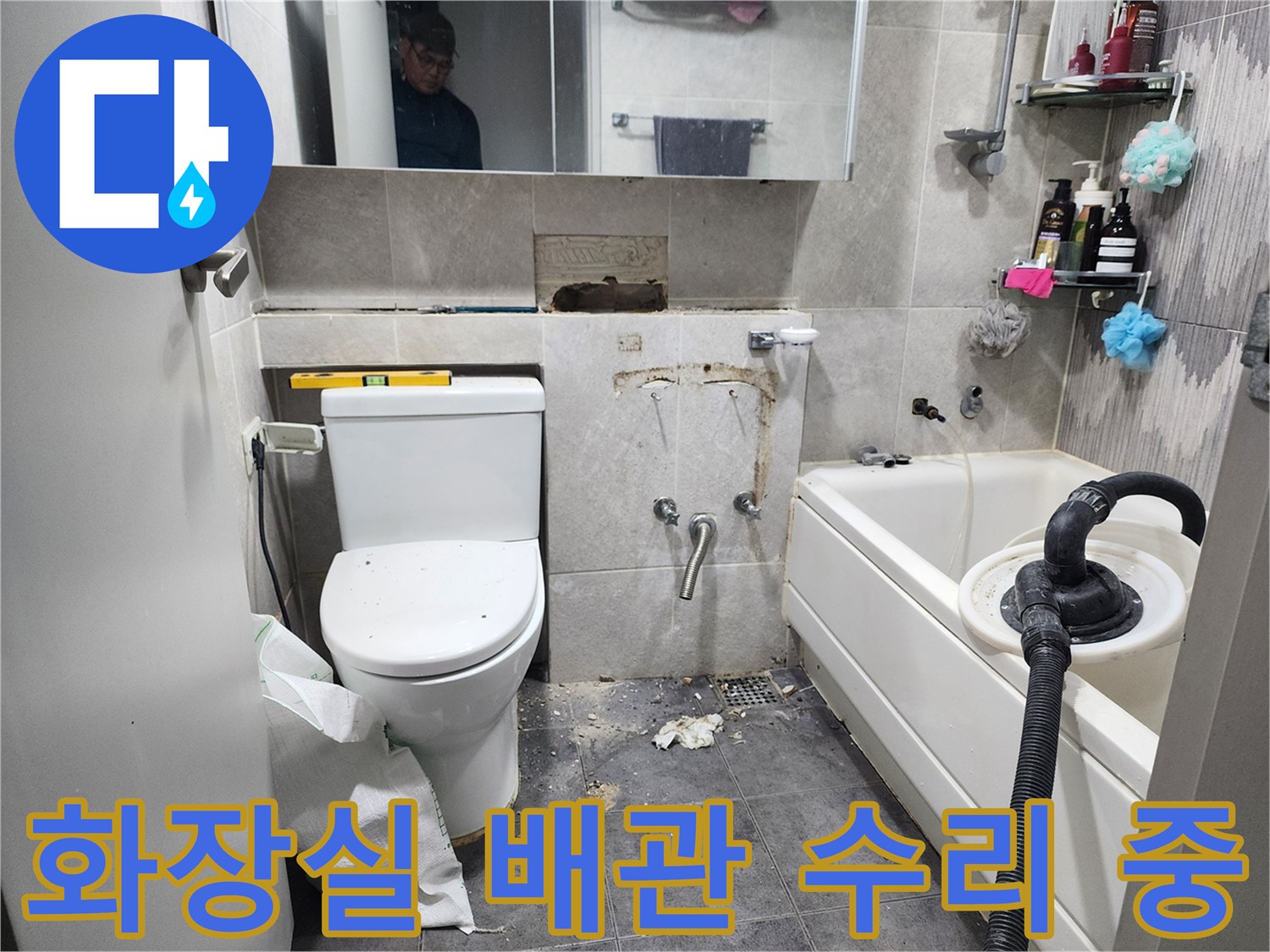 이 이미지는-동대문구의 한 아파트 화장실에서-누수 발생 지점의 타일을 제거하고-손상된 배관을 수리하기 위해-작업 중인 현장을 보여줍니다