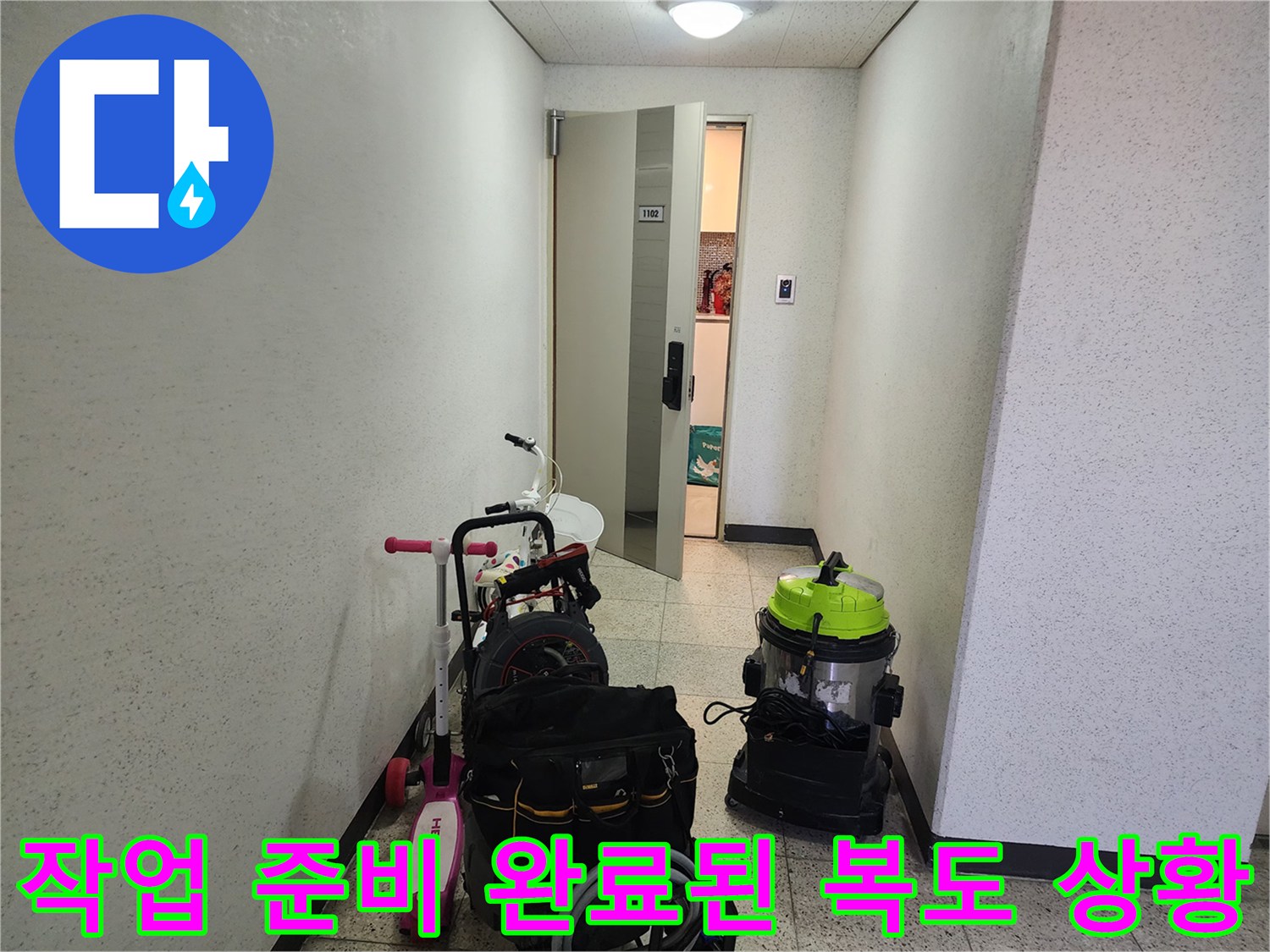 배관 세척용 장비와 공구함이 놓인 건물 내부 통로