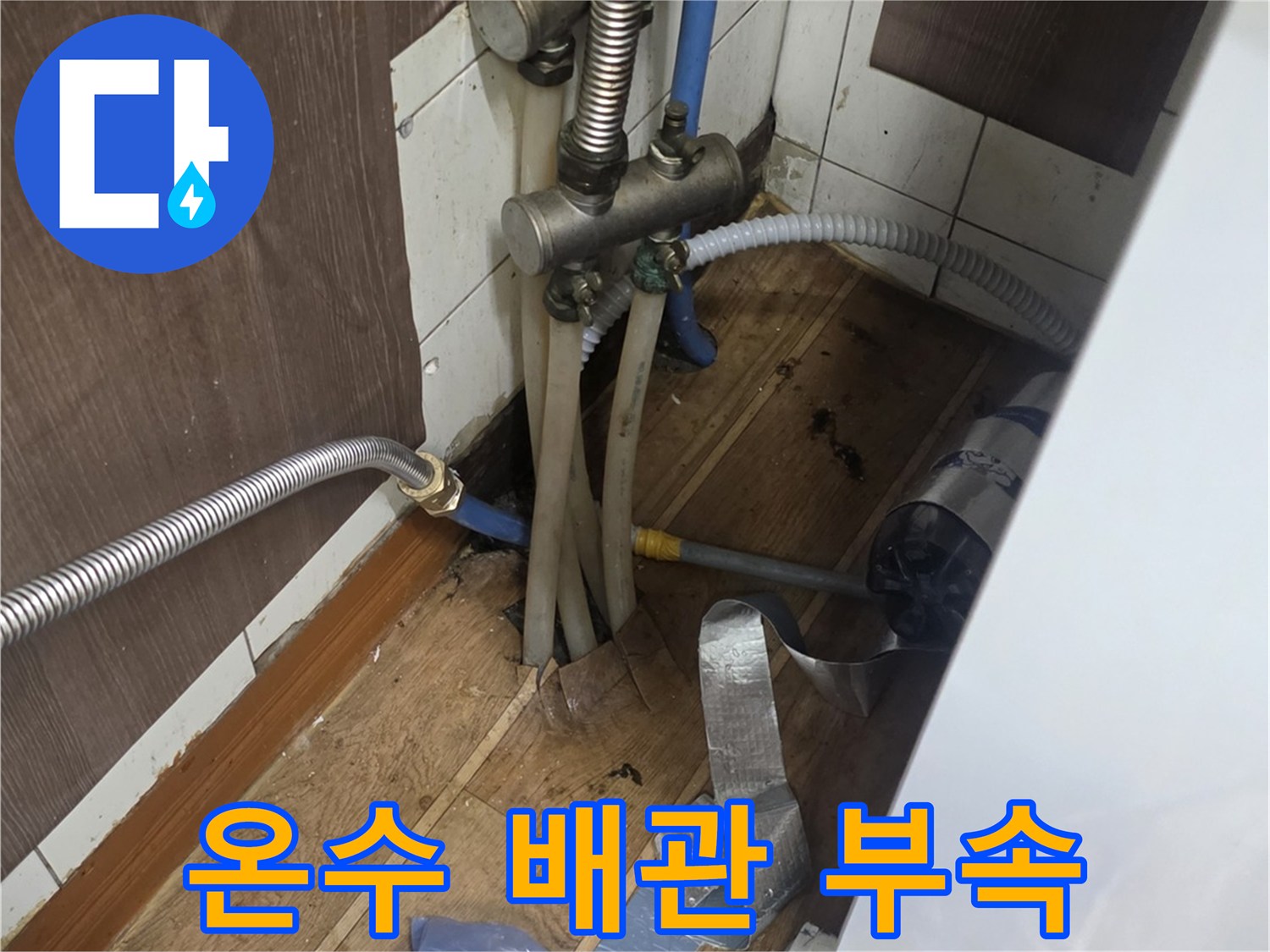 주방 하부장 내부에 노출된 은색 자바라 배관과 연결 부위