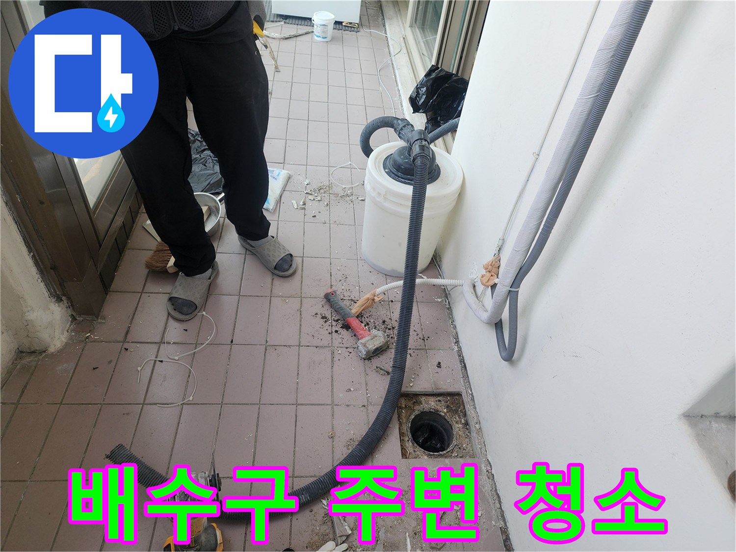 작업자가 베란다 바닥의 배수구 근처 이물질을 제거하며 점검하고 있습니다.