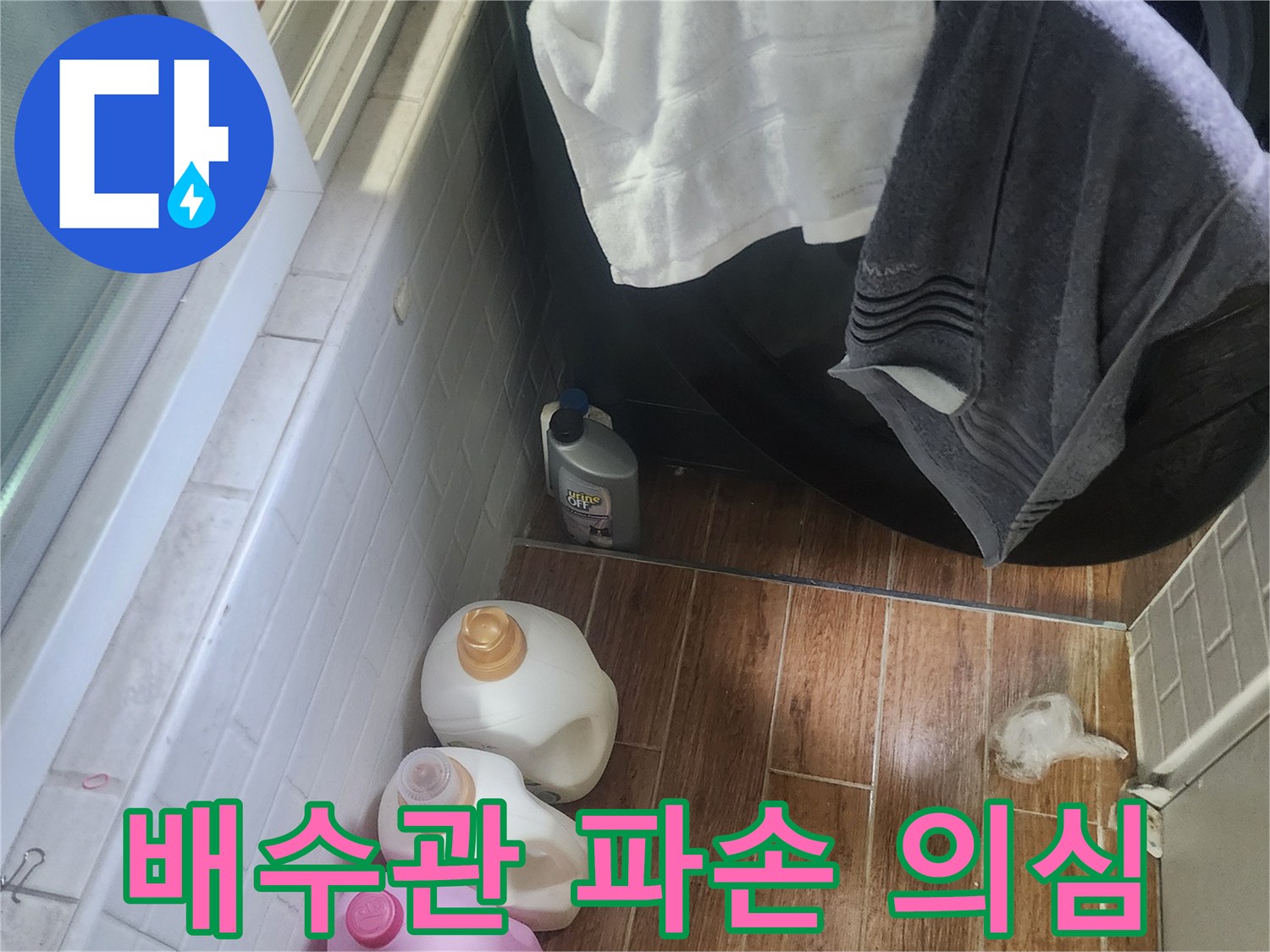 세탁실 바닥에 물이 고여 있고-세제 용기들이 놓여 있는 누수 발생 현장입니다.