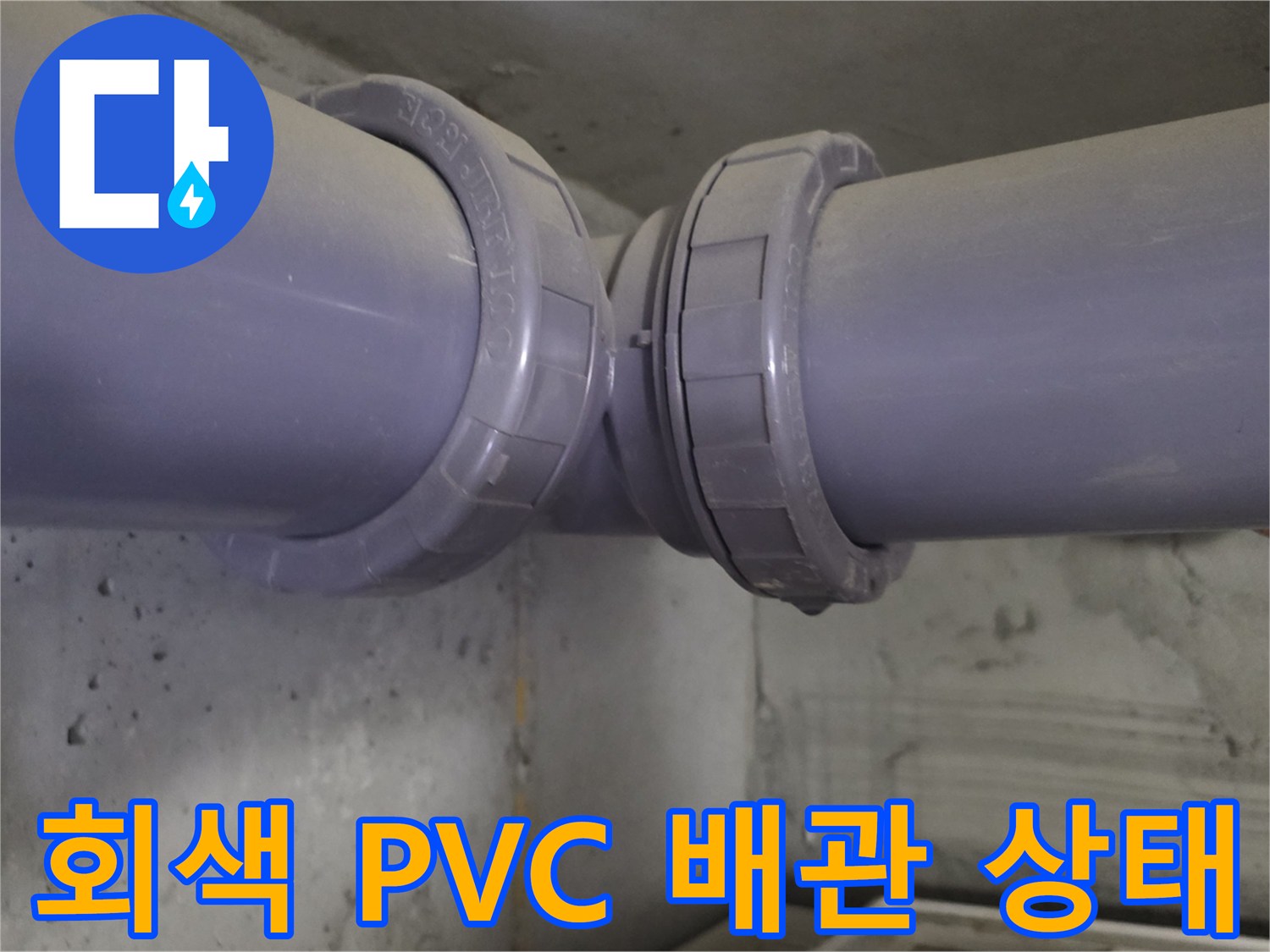 천장에 설치된 회색 PVC 배관의 연결 이음매를 근접 촬영하였습니다.