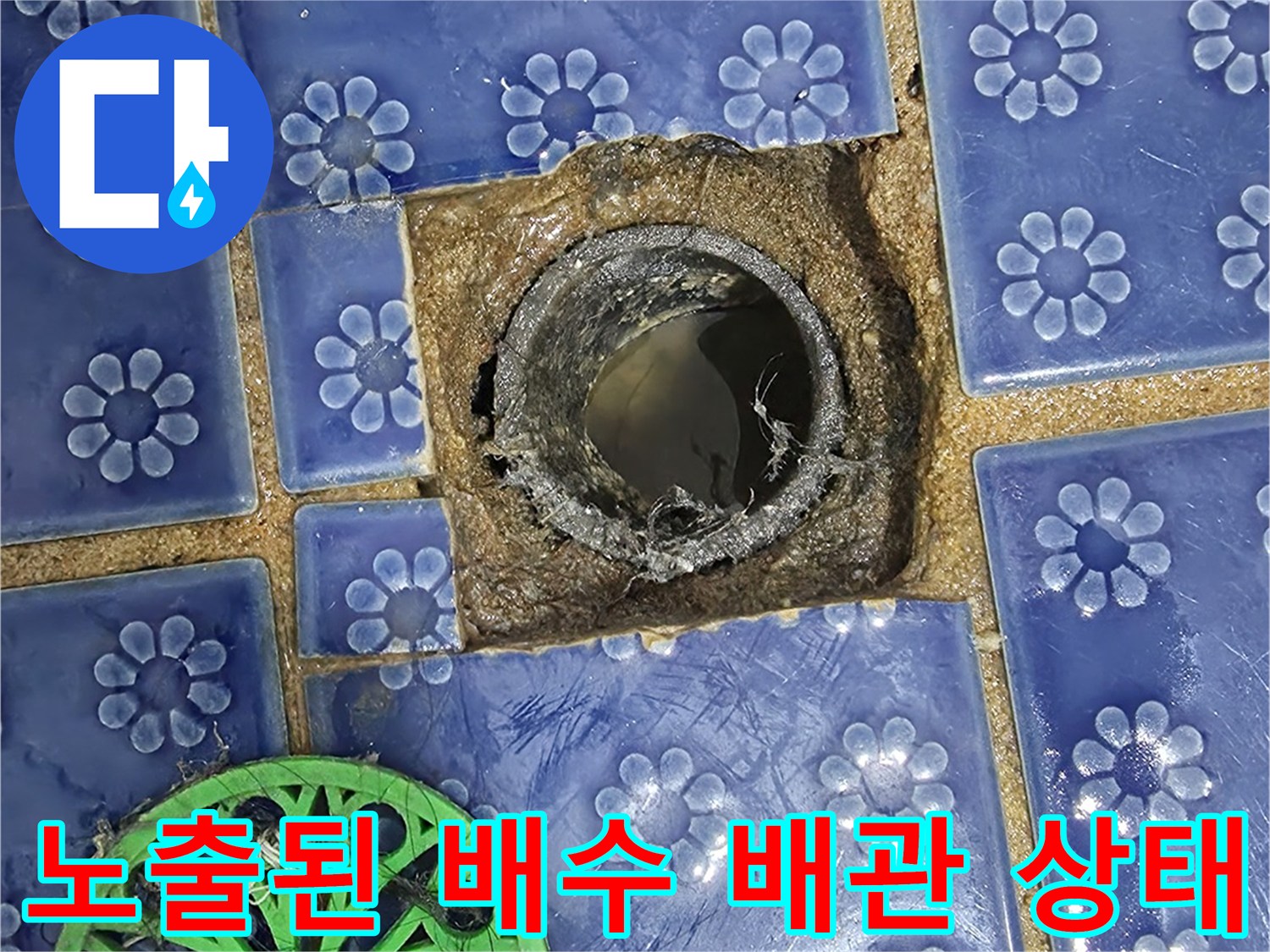 푸른색 꽃무늬 타일과 검은색 배수 배관의 접합 부위
