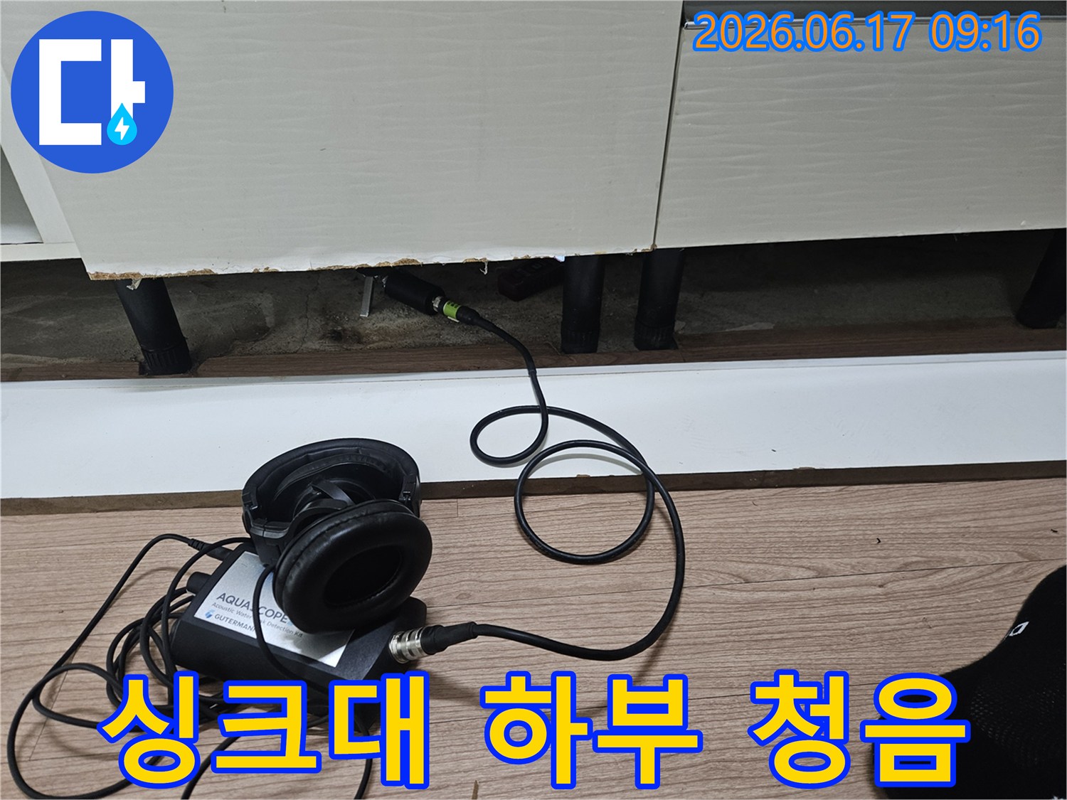 누수 엔지니어가-싱크대 하부장 아래-청음식 탐지 장비로-배관 누수음을 듣고 있습니다.