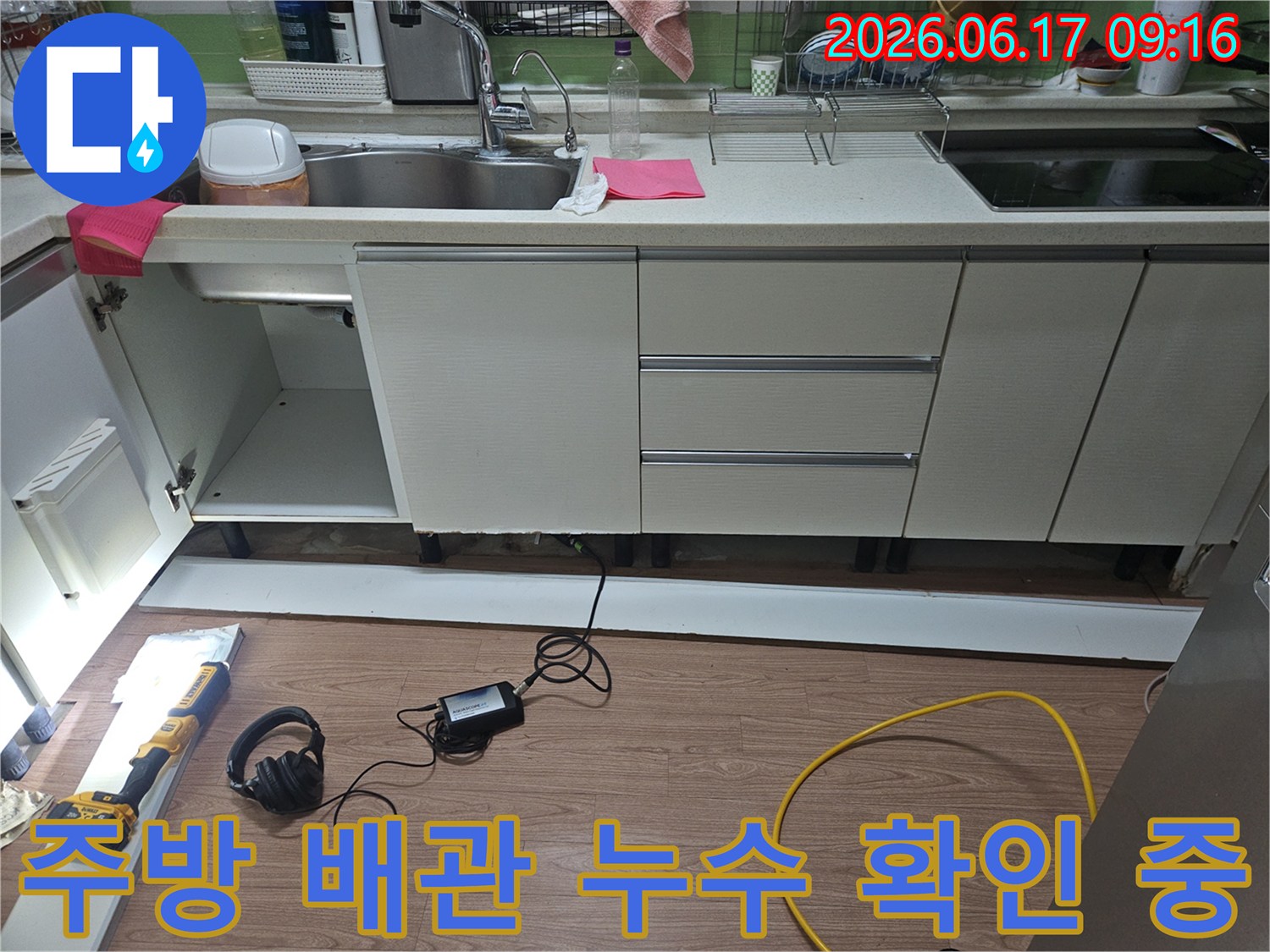 주택 싱크대 하부에서-누수 여부를 확인하기 위해-개방된 공간에서-전문 장비를 활용하여-배관 상태를 점검하는 모습