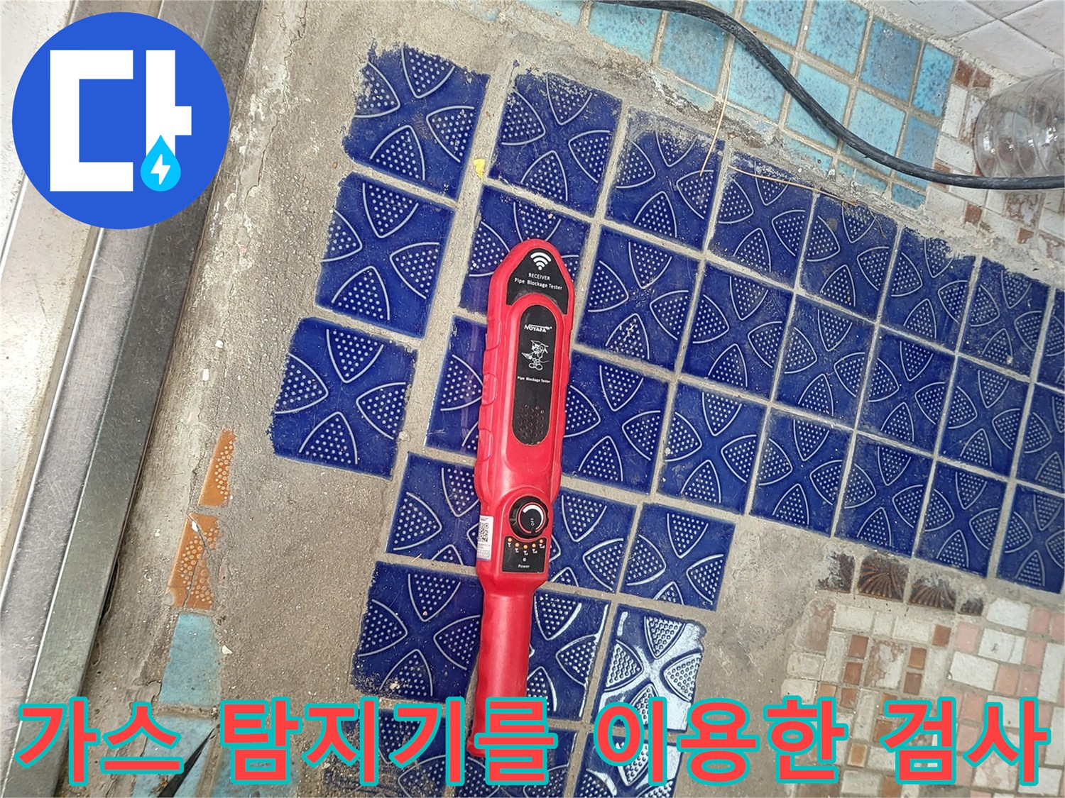 푸른색 욕실 타일 위에 놓인 빨간색 가스식 탐지 장비