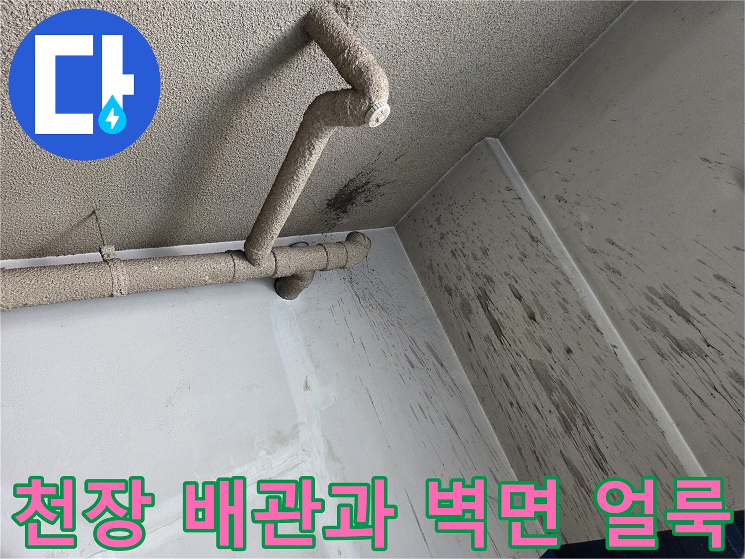 배관 주변 벽면에 발생한 어두운 색의 오염물 흔적 사진입니다.