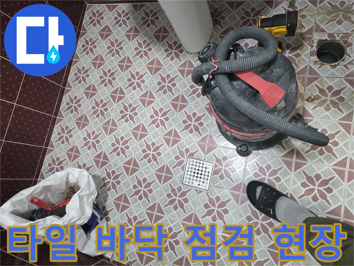 작업 중인-화장실 바닥의 배수구와 청소용 진공청소기