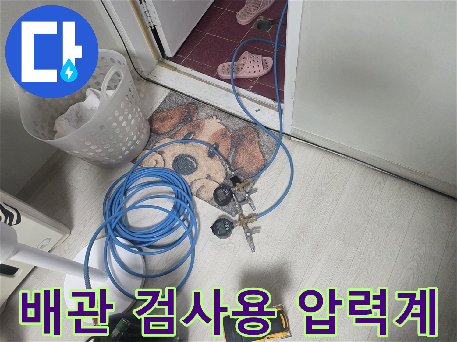 화장실 입구에 놓인-배관 상태를 확인하기 위한-압력 게이지와 호스