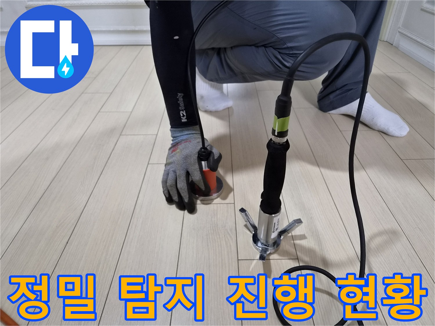 바닥재 위에서 가스 탐지 장비를 통해 누수 지점을 추적하는 장면입니다.