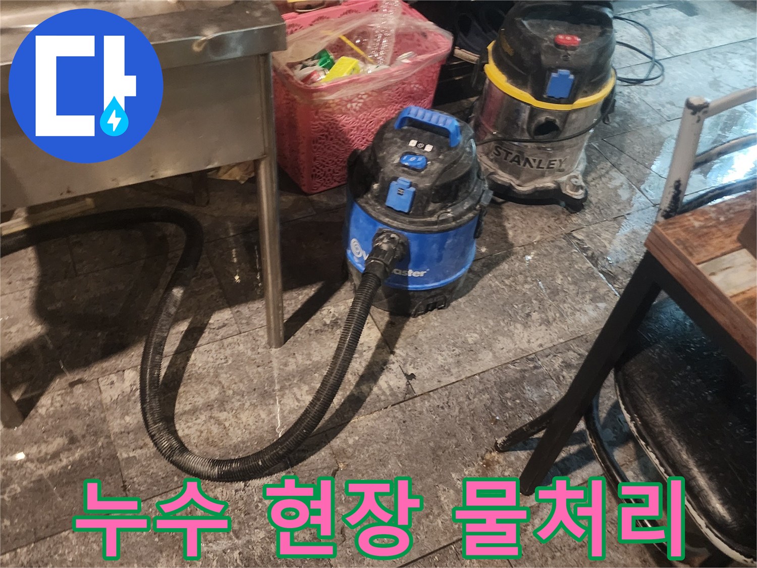 누수 피해 현장에서-바닥에 고인 물을-신속하고 깨끗하게-제거하기 위해-사용되는-전문 석션 장비 두 대가-작업을 기다리고 있습니다.