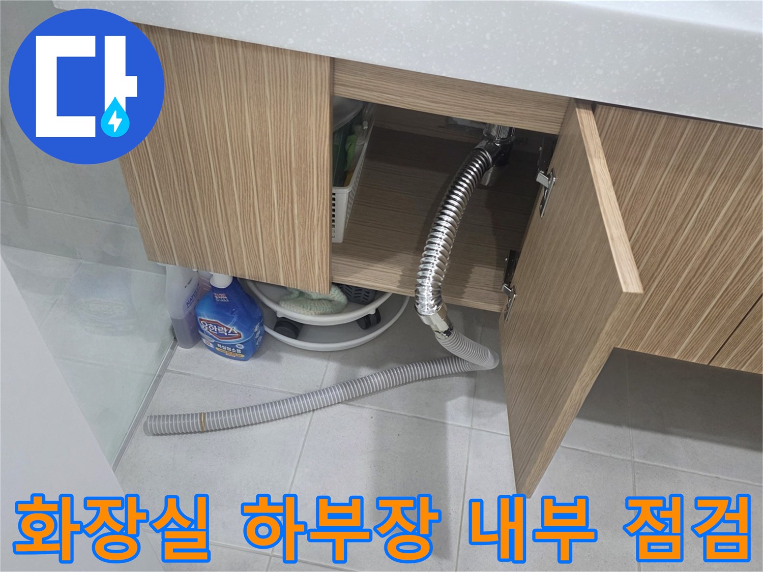 세면대 아래쪽 하부장 문을 열고 배관을 관찰하는 모습