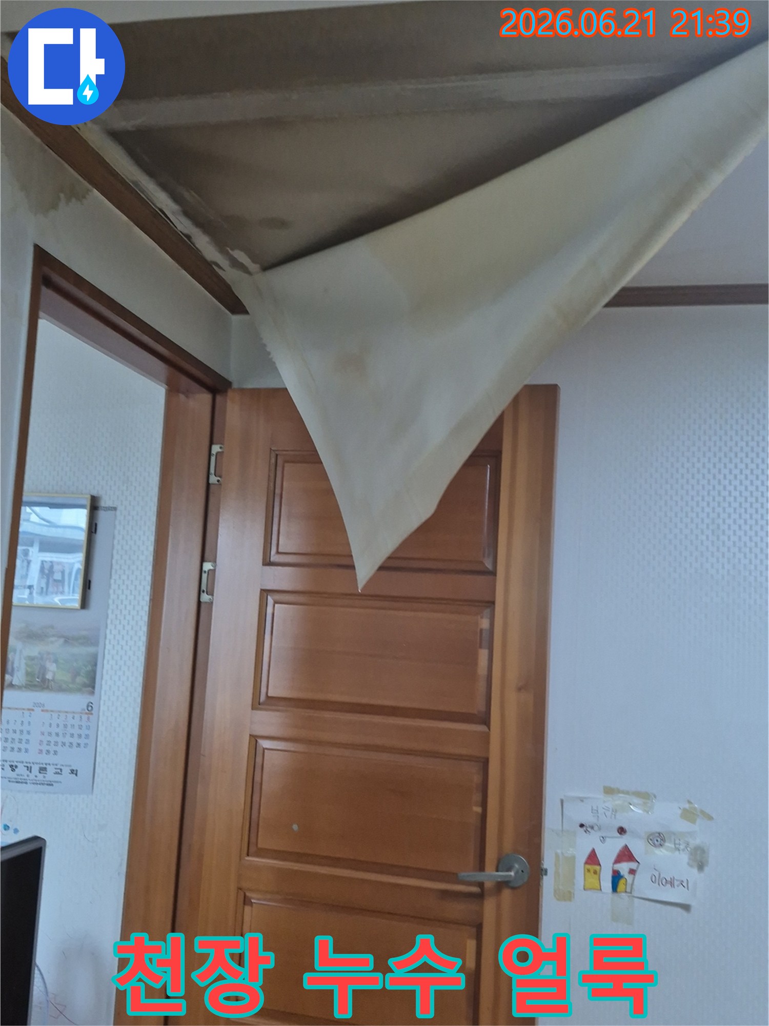 천장 벽지가 물에 젖어 심하게 처지고-넓게 퍼진 얼룩이 선명하게 보이는 모습이 담긴 사진