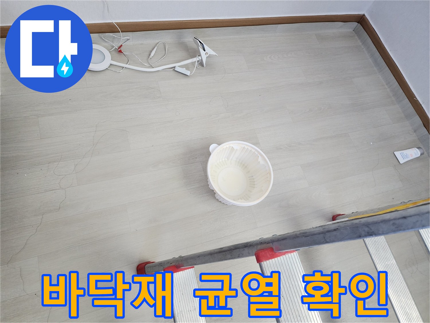 거실 바닥 마루의 갈라진 틈과 작업용 사다리 모습