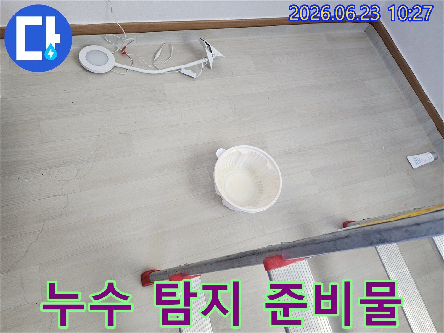 천장에서 떨어지는 물을 임시로 받는 그릇과-누수 지점 확인을 위한 사다리-정밀 탐지를 위한 조명 장비가 바닥에 놓여 있는-누수 공사 전 준비 모습입니다