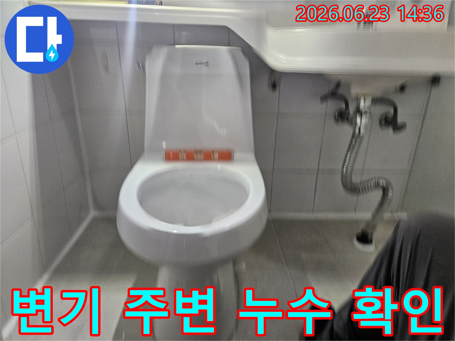 이 사진은 화장실 변기 주변에서 발생한 누수 현상을-전문가가 면밀히 검토하고 있는 모습을 보여줍니다.