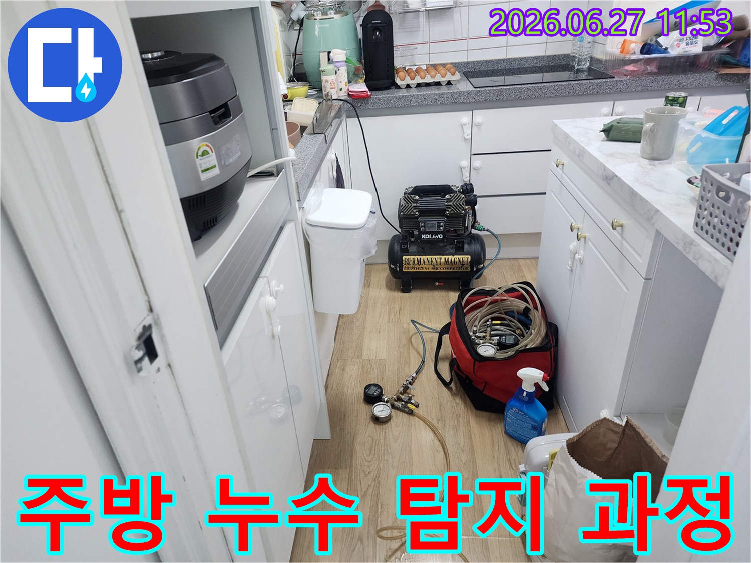 주방 바닥에 설치된 누수 탐지 장비와-배관 연결 모습으로-정밀한 누수 진단 과정을 보여줍니다.