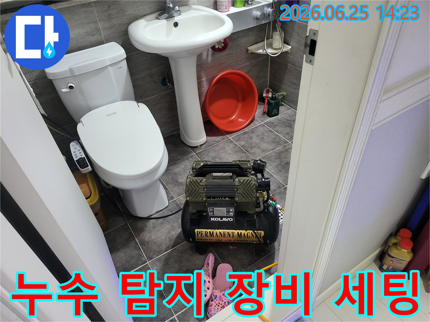 변기와 세면대 옆에 놓인-누수 탐지용 콤프레셔 장비가-작동 대기 중인 욕실 풍경