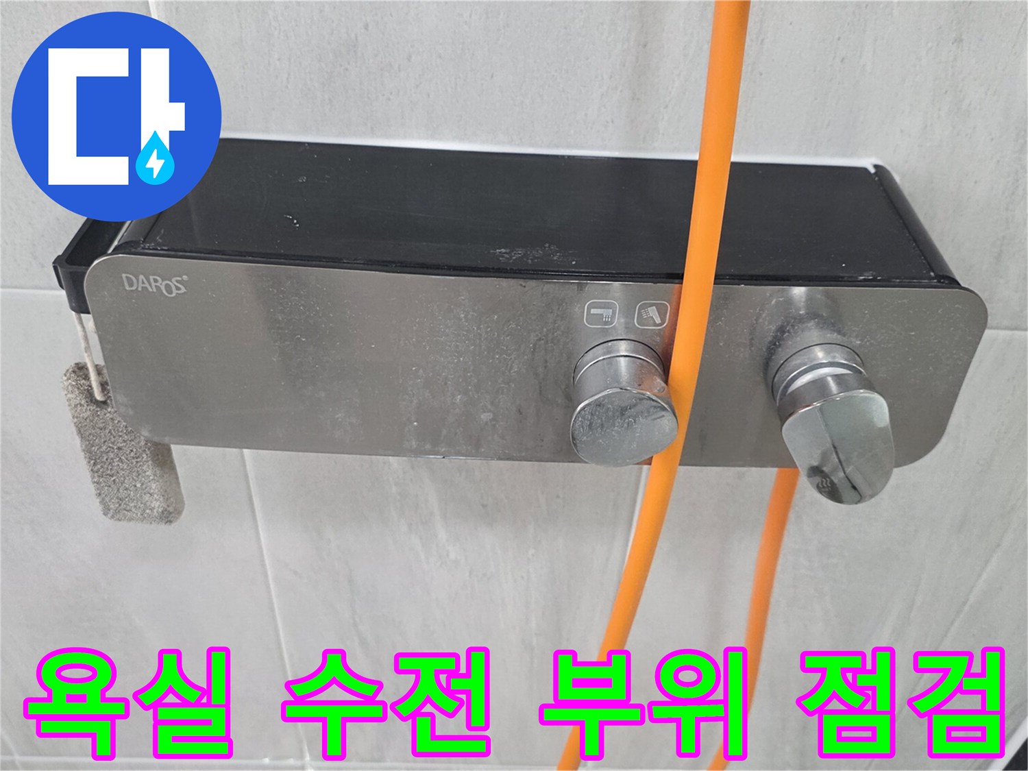 욕실 벽면에 설치된 은색 수전과 주황색 호스 상태 확인