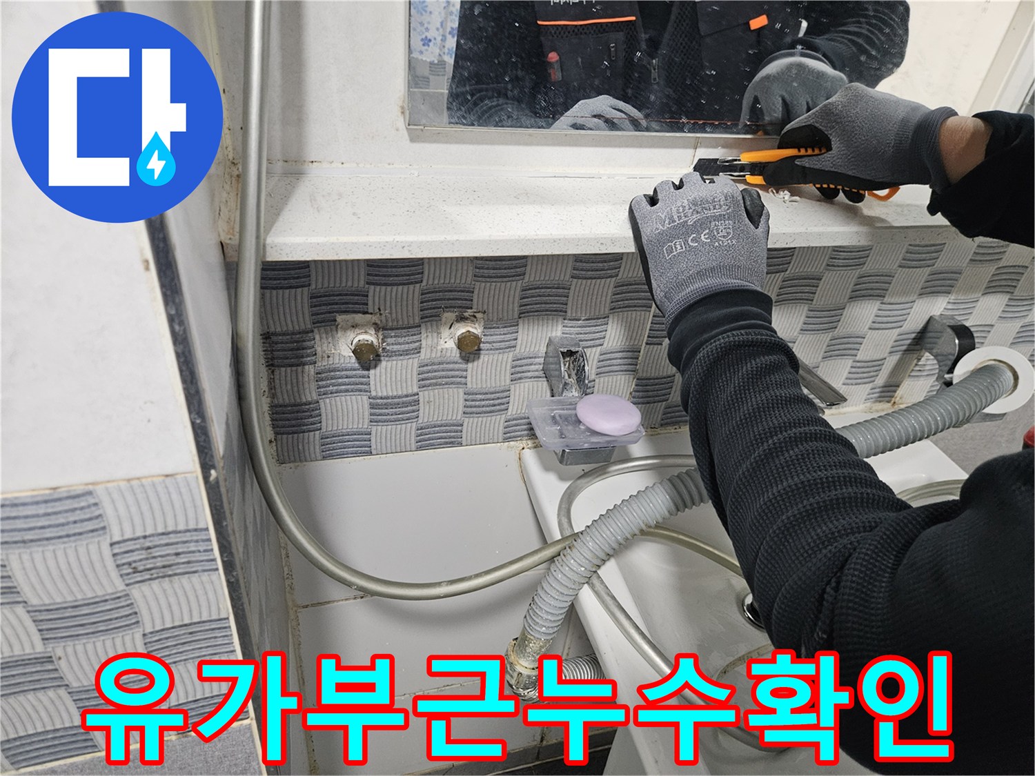 작업자가 장갑을 착용하고 배관 부위의 틈새를 조사하는 장면입니다.