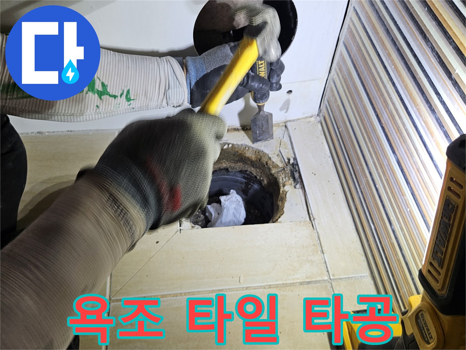 작업자가 도구를 사용하여 욕조 옆면 타일을 제거하는 모습입니다.