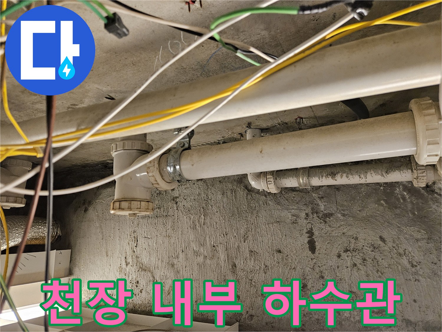 천장에 노출된 흰색 PVC 파이프와 전선들이 복잡하게 얽힌 모습