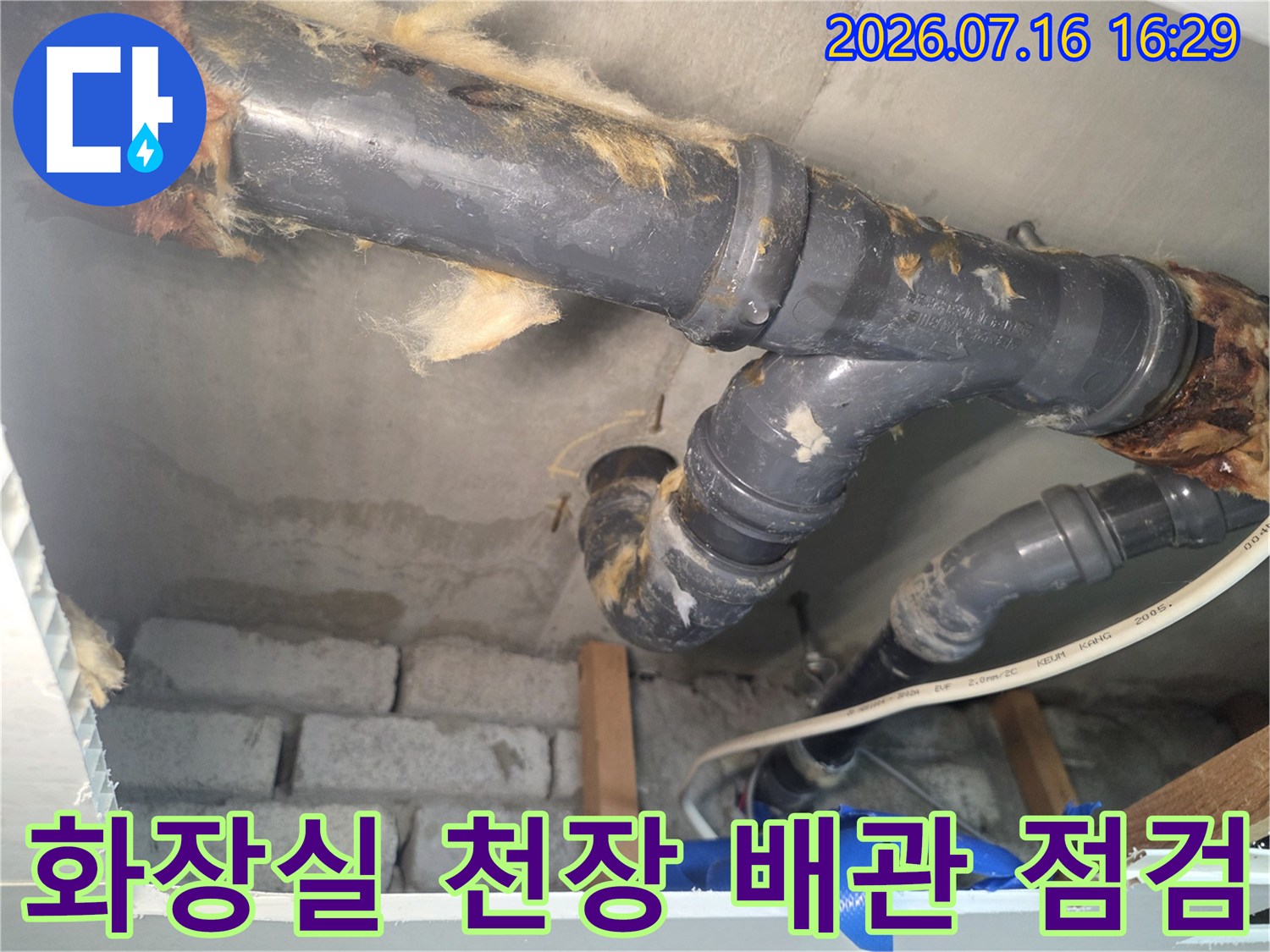 화장실 천장 내부의 노출된 배관과 연결 부위를 정밀하게 점검하는 모습