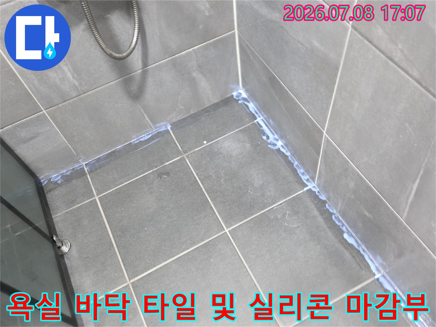 회색 타일과 투명한 실리콘이 적용된 욕실 모서리 부분