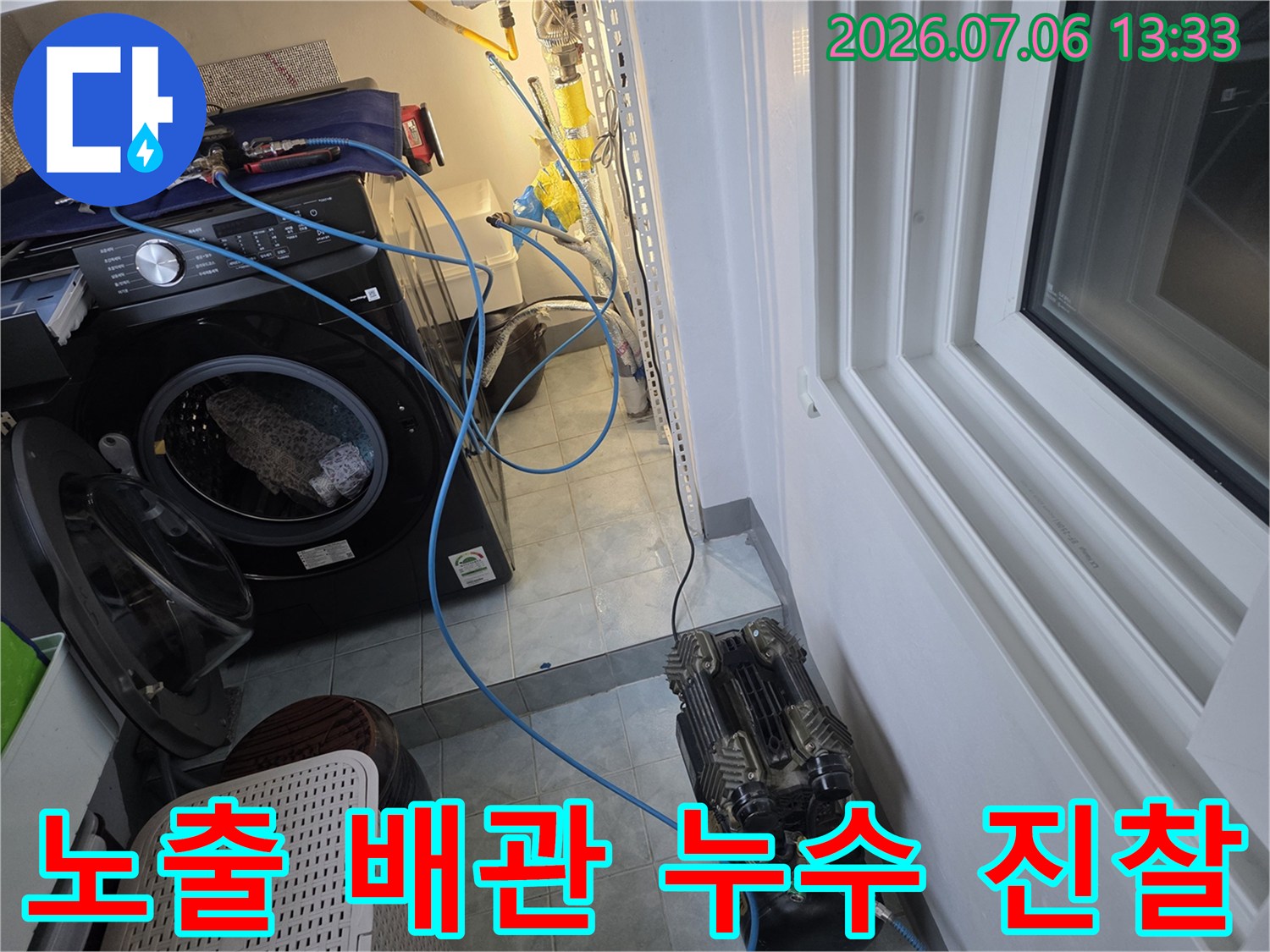세탁기 옆에 위치한 여러 갈래의 배관들을 정밀하게 점검하는 모습
