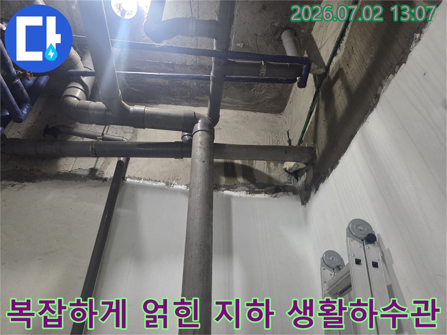 천장에 수직과 수평으로 교차 설치된 회색 PVC 배관-지하 공간의 전반적인 모습