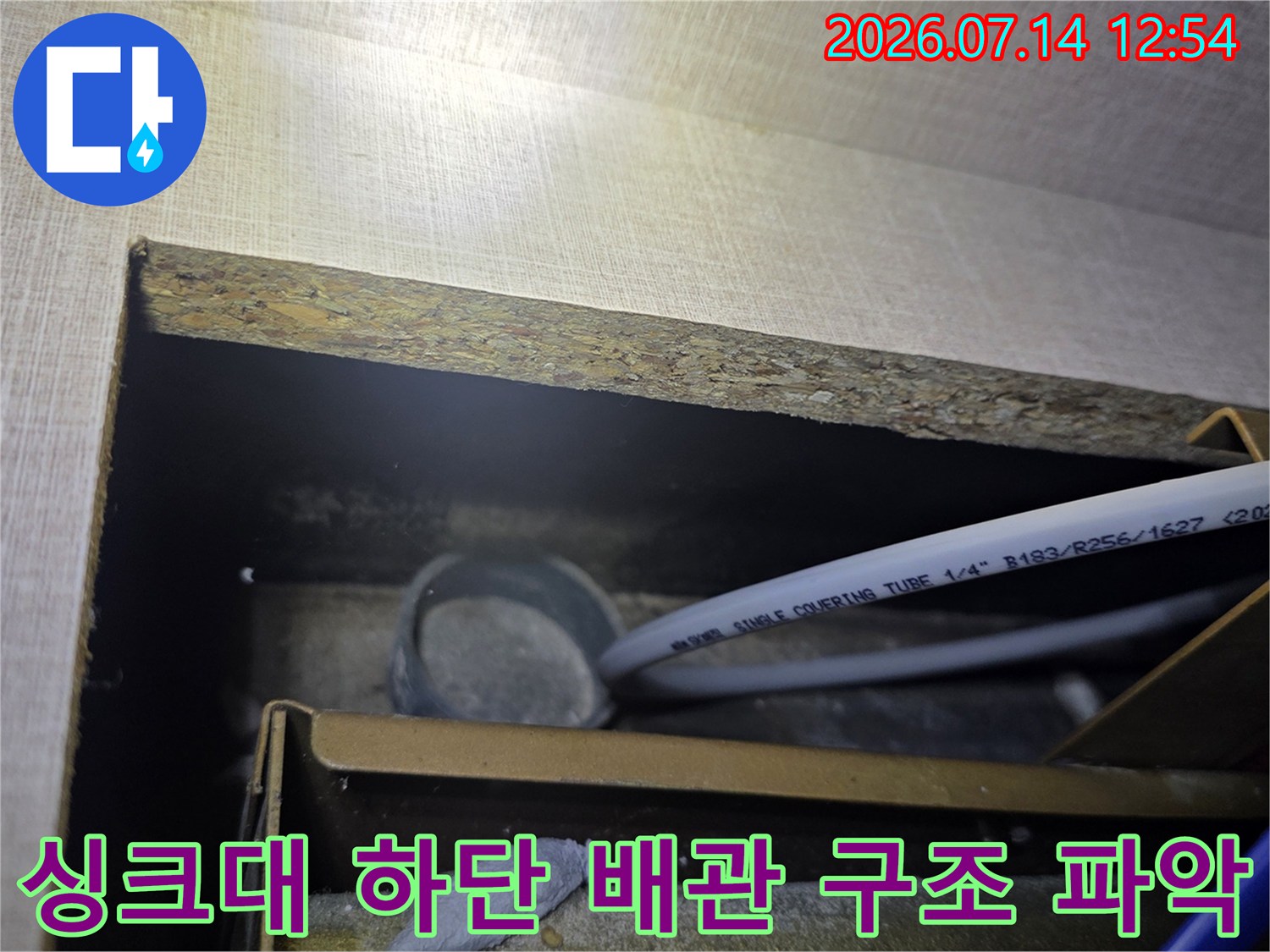 싱크대 아래쪽 공간에 배치된 배관들의 연결 상태를 분석하는 현장 사진