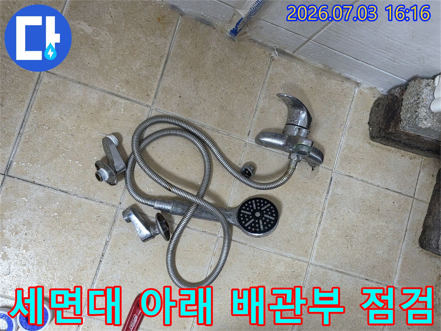 분리된 세면대 호스와 렌치 등 공구와 함께 있는 배관 부품들