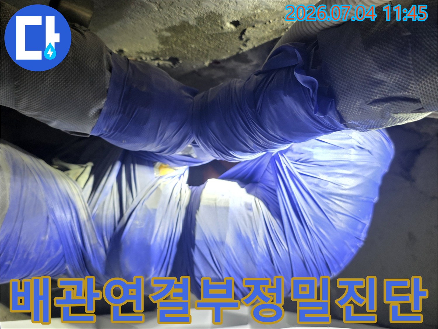파란색 보호재로 감싼 화장실 천장 내 배관 수선 현장