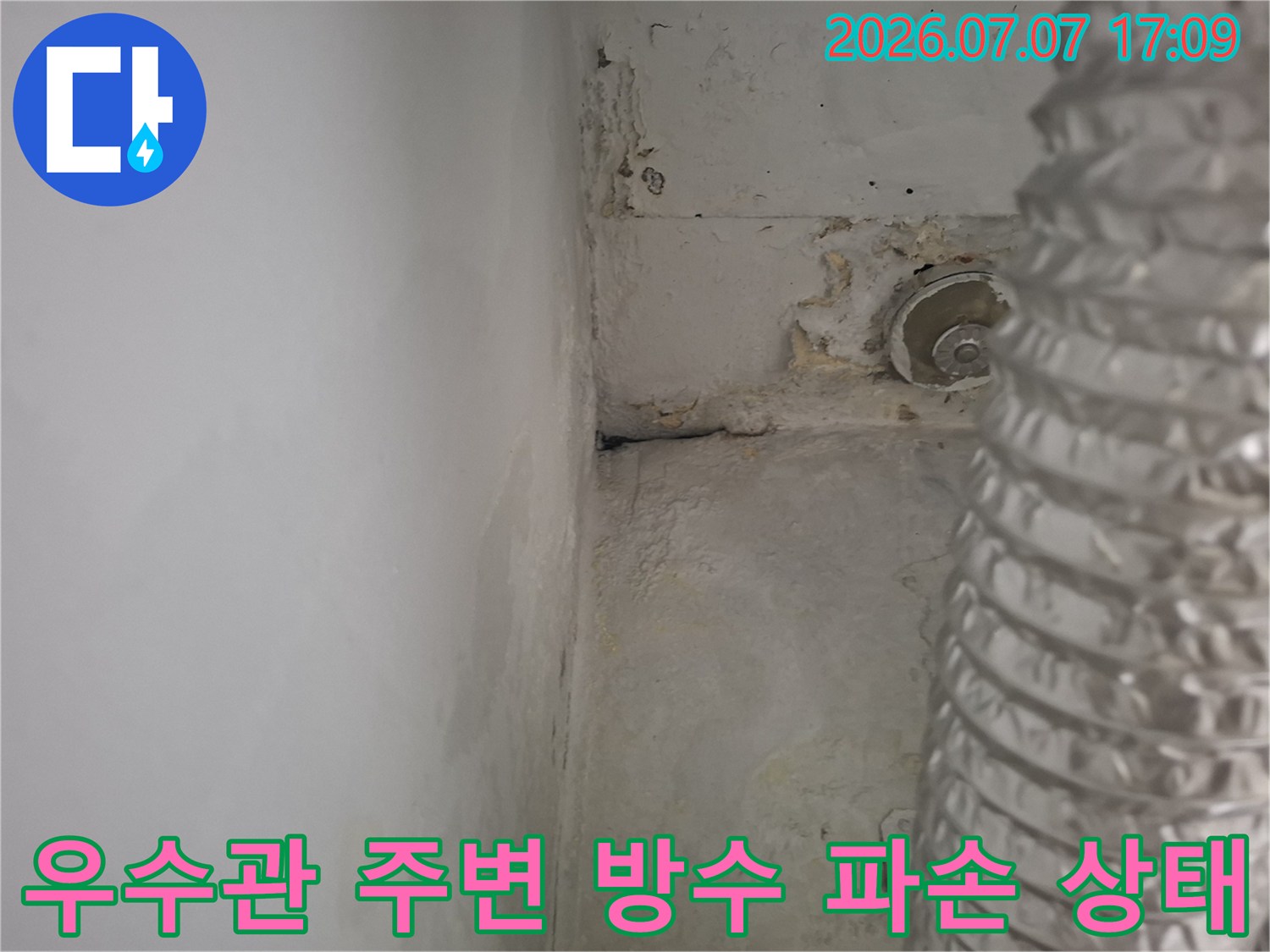 훼손된 우수관 주변 마감재와 배관 노출 상태