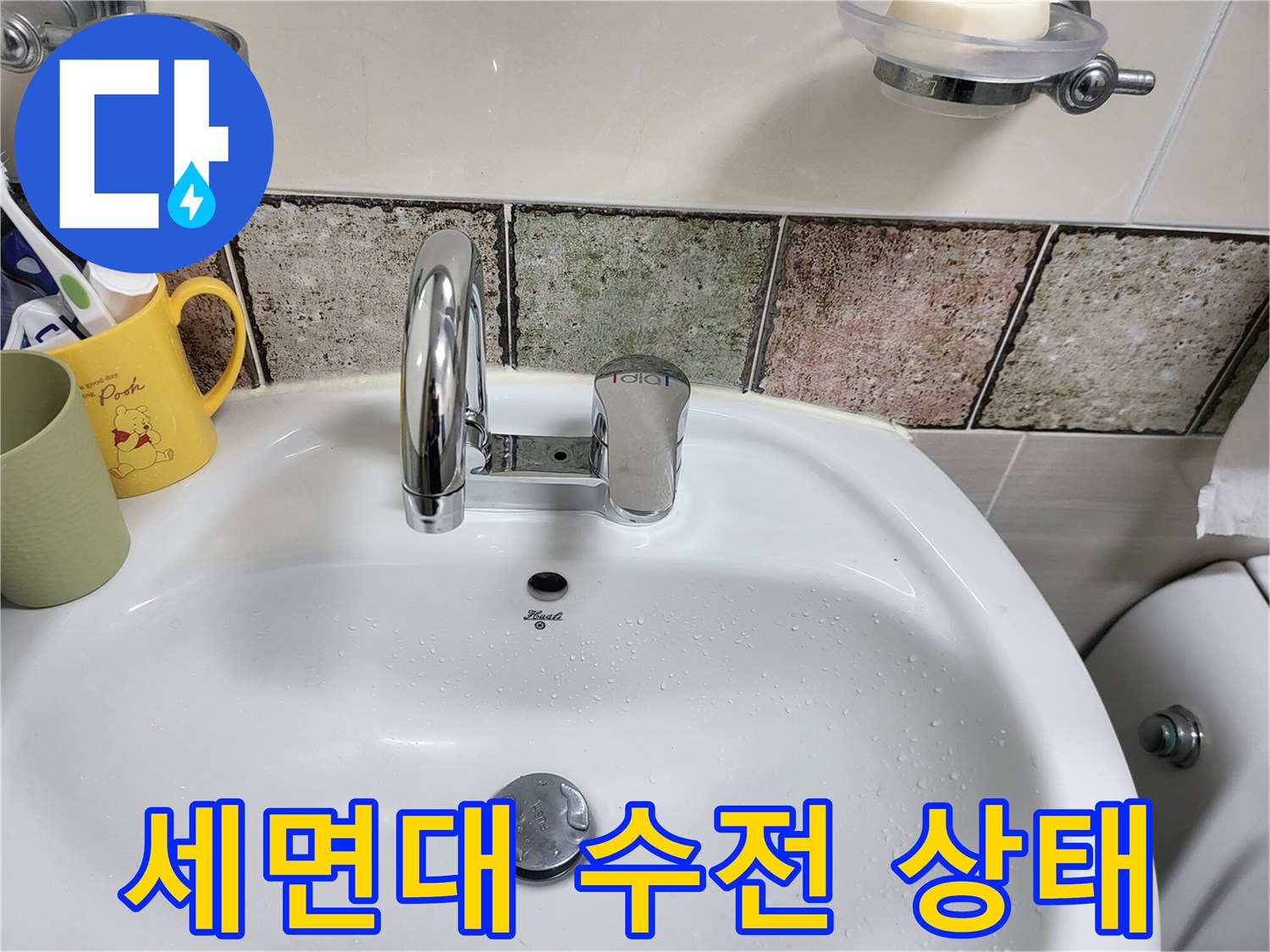 물기가 맺혀 있는 세면대 수전과 타일 모습입니다.