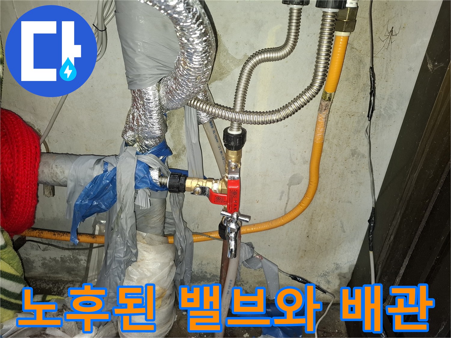 붉은색 밸브가 장착된 노후된 금속 배관 연결 부위