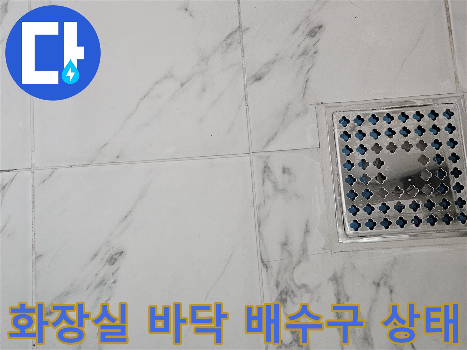 하얀색 대리석 패턴 타일과 금속 배수구 덮개가 위치한 모습