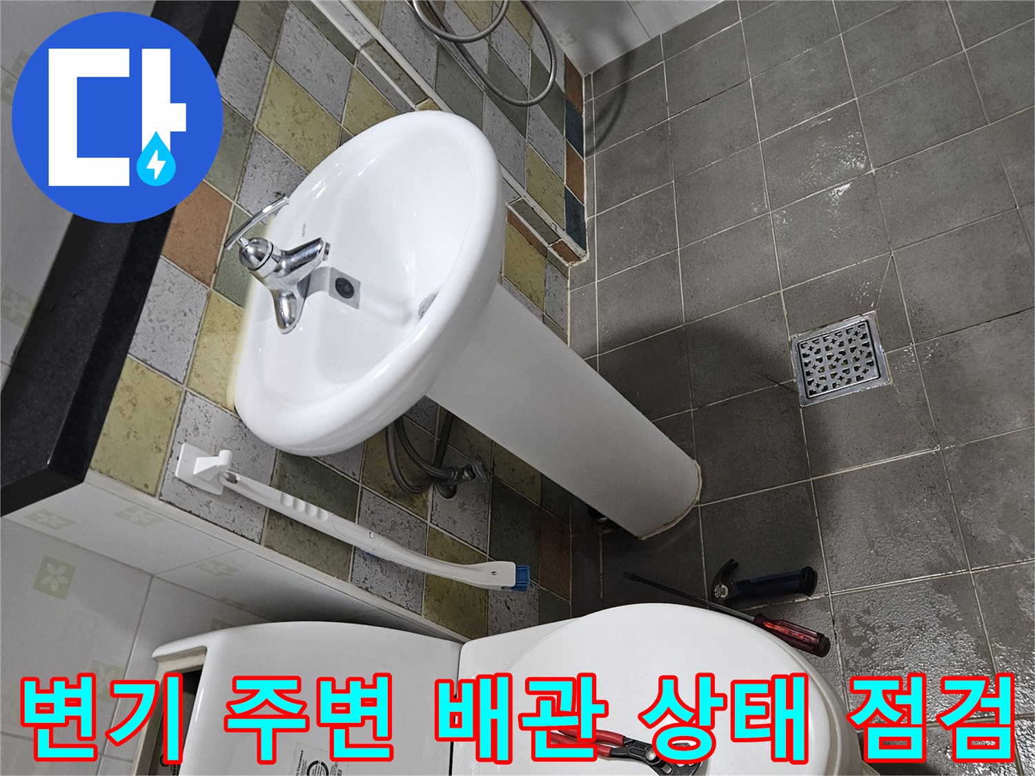 화장실 변기 하단 - 세면대와 변기 근처의 배관 연결 부위를 점검하고 있습니다.