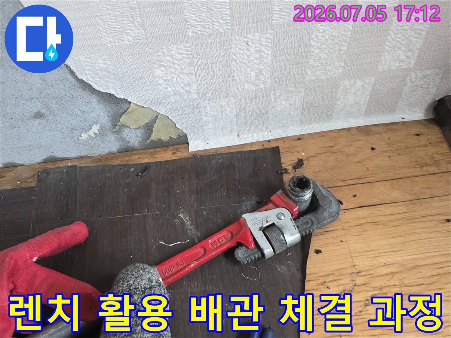 배관을 고정하기 위해 붉은색 장비로 연결 부위를 조이는 모습