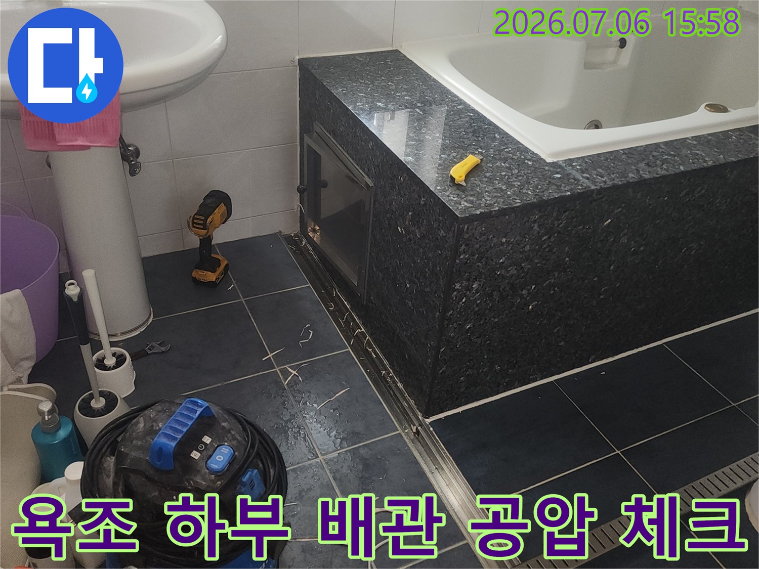 배관 압력 측정기 및 작업 도구가 배치된 욕조 아래 공간