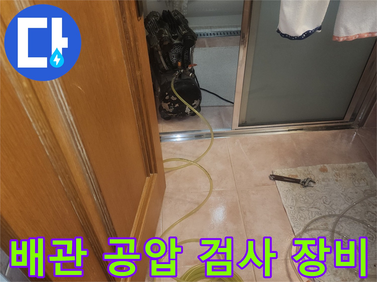 분홍색 호스가 연결된 디지털 압력계와 작업용 렌치